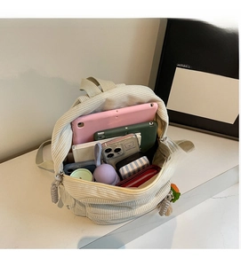 Interior view showing the large capacity of the beige corduroy backpack with essentials