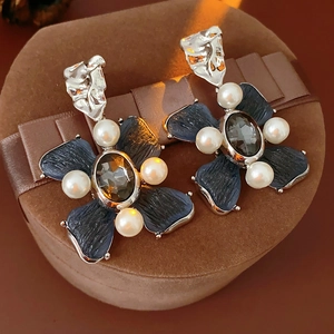 Detailed macro view of vintage flower pearl earrings on a brown velvet jewelry box
