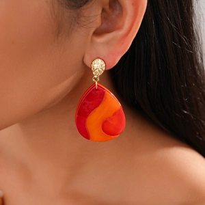 Close-up of geometric teardrop earrings with red and orange marbled resin texture