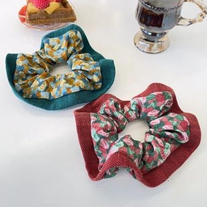 Detailed view of floral red and patterned teal fabric scrunchies on a white table