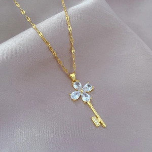 Macro detail of luxury golden clover key pendant necklace with sparkling zircon crystals