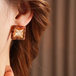Close-up of square amber resin earring with faceted crystal on model ear