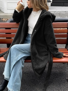 Détail d'un manteau noir à capuche en fausse fourrure avec ceinture sur mannequin