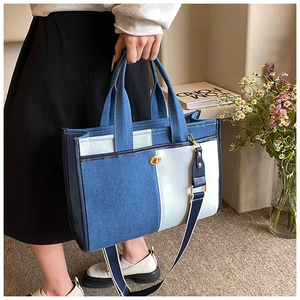 Détail d'un sac cabas en denim bicolore avec fermoir rotatif et bandoulière amovible