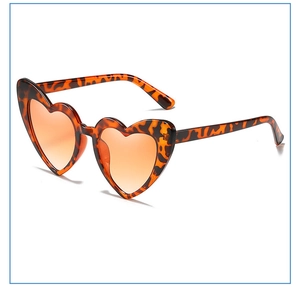 Detail of heart-shaped sunglasses featuring leopard frame and orange gradient lenses