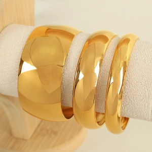 Three-piece gold titanium steel polished bangle set with varying widths on display