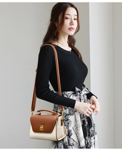 Brown and white crossbody bag with gold lock shown with elegant floral skirt