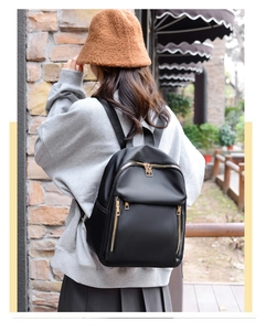 Outdoor shot showing a black nylon backpack with gold zippers on a model's back