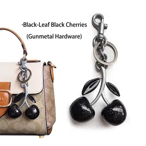 Detail of black cherry bag charm with gunmetal hardware and glitter resin finish