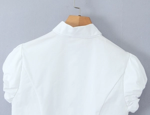Detail view of the back of a white puff-sleeve shirt with a classic turn-down collar