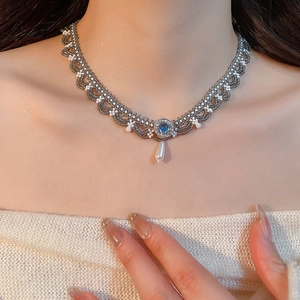 Close-up of retro lace choker with blue gemstone and white teardrop pearl pendant