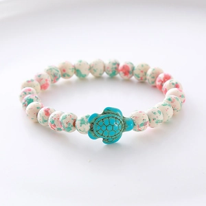 Detailed close-up of a white marbled bead bracelet featuring a turquoise turtle charm