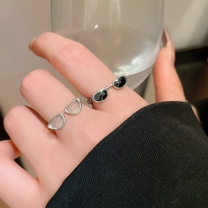 Detail of creative silver eyewear rings in black and clear lenses worn on fingers