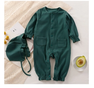 Dettaglio del set tutina neonato a coste verde scuro con cappello a balze su pizzo bianco