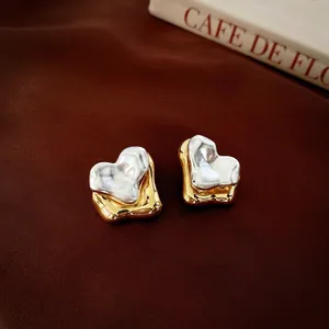 Lava design heart stud earrings in gold and silver plating on red velvet background