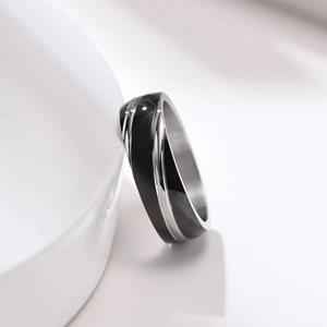 Macro shot of minimalist stainless steel ring with black enamel inlay on white stand