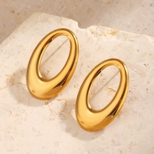 Polished gold geometric oval hoop earrings displayed on a minimalist textured stone