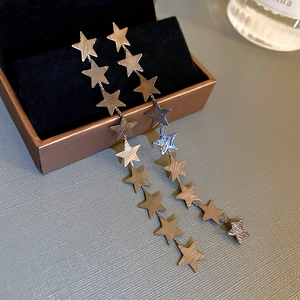 Detailed macro shot of long metal tassel earrings featuring a multi-layer star design