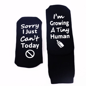 Detail of funny pregnancy slogan socks in black knit with non-slip lettering and icons