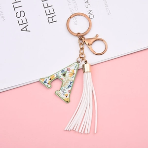 Close-up of letter A keychain with rose gold hardware, floral patterns and white tassel