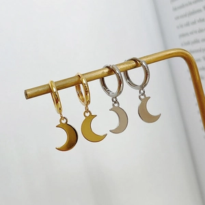 Detail of gold and silver crescent moon hoop earrings on a metal display stand