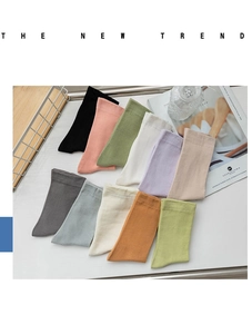 Flat lay of cotton crew socks in eleven soft pastel colors with lifestyle props