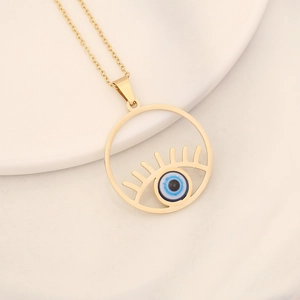 Detailed close-up of golden evil eye pendant with blue bead on white ceramic tray