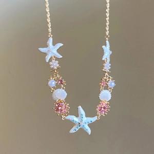 Detail of nautical necklace with shell, starfish, pearl and crystals on gold chain