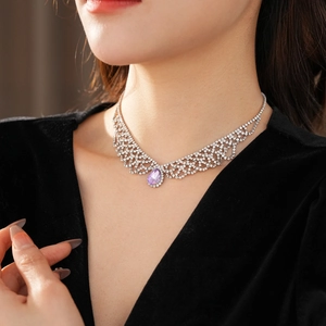 Vista macro della collana argento con gemma a goccia viola e diamanti sulla modella
