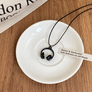 Collier minimaliste avec un pendentif casque noir créatif sur un fond de bois