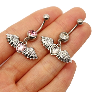 Macro shot of silver heart navel rings with pink and clear crystals held in a palm