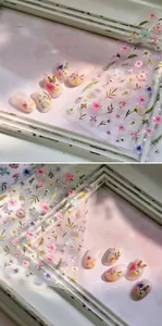 Detail of 3D embossed floral nail stickers with gold accents on pink gradient nails