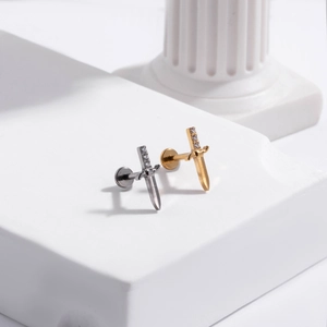 Macro detail of sword-shaped G23 titanium ear studs with inlaid clear gemstones