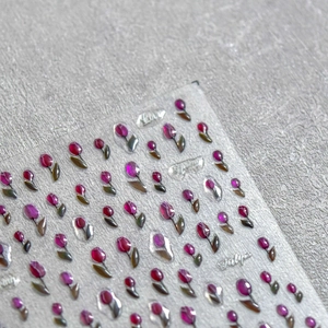 Macro detail of 3D embossed nail stickers featuring purple tulips and floral patterns