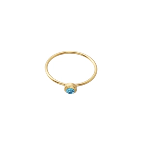 Detail of minimalist gold ring featuring a bezel-set round blue birthstone on white background