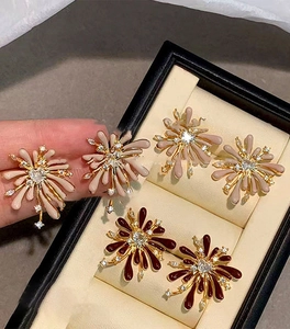 Close-up of red and beige enamel flower stud earrings with zircon crystals in jewelry box