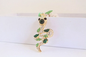 Macro shot of gold snake keychain with sparkling clear and green rhinestones