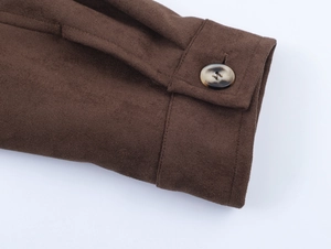 Detailed close-up of brown faux suede sleeve cuff with an amber-toned button and stitching