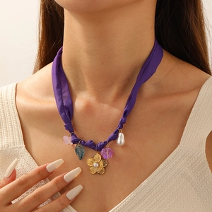 Detail of bohemian purple fabric necklace with gold flowers and baroque pearls