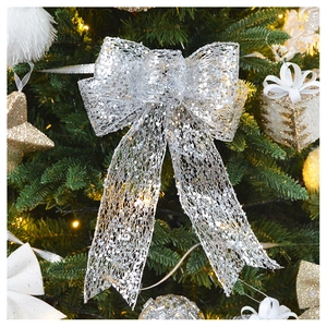 Close-up of sparkling silver sequin bow ornament hanging on a lush green Christmas tree
