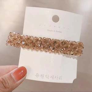 Macro detail of hand-woven champagne crystal hair clip with polished metal base