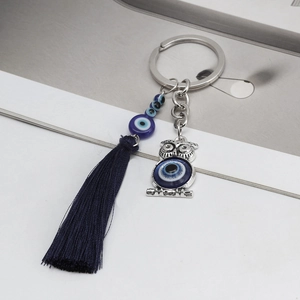 Detailed view of an owl evil eye keychain featuring blue beads and a long silk tassel