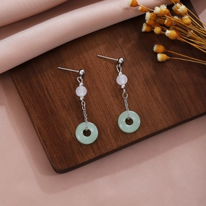 Detail of long drop earring featuring a green jade ring and white pearl tassel on silk