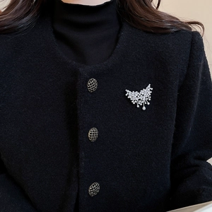 Detail of zircon butterfly brooch with pearl tassel on black tweed jacket for elegant style