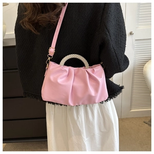 Detail of pink pleated handbag with pearl handle and metal strap buckle on tweed jacket