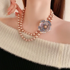 Detail of vintage champagne pearl necklace with a purple floral brooch and gemstones