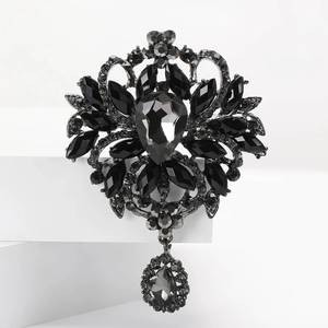 Détail d'une broche fleur vintage avec cristal noir en goutte et pendentif métal