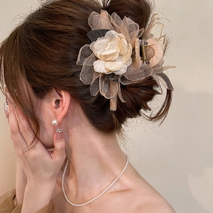 Elegant large rose hair claw clip in beige organza and grey leaves on a model's hair