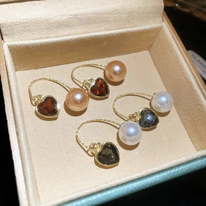 Détail de boucles d'oreilles cœur en pierre et perle avec crochets en U dorés