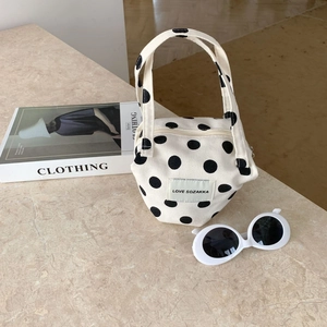 Close-up of beige polka dot canvas handbag with branded woven label on marble surface